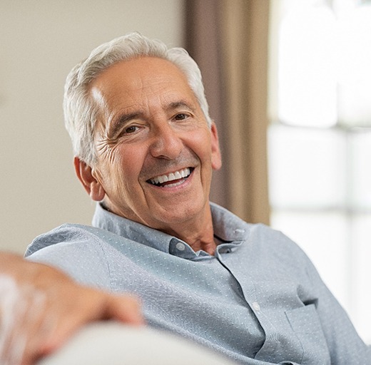older man smiling while sitting inside
